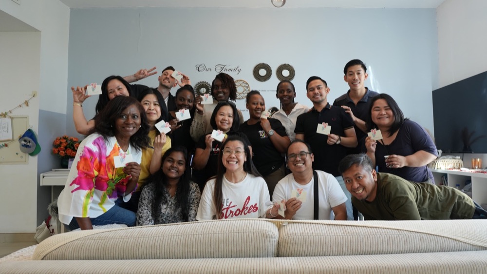 The Koinonia family gathered together, holding handmade cards